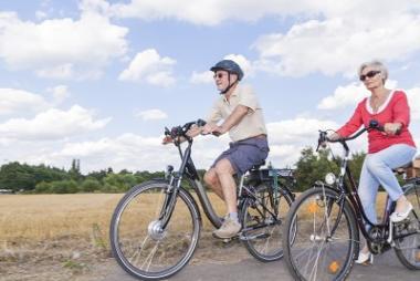 Senior couple wearing sunglasses while cycling side by side in the countryside