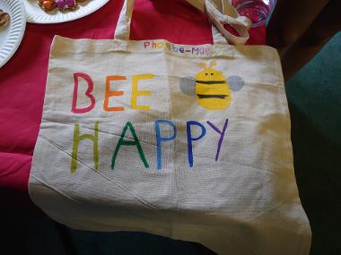 A tote bag with the words 'Bee Happy' and a bee drawn on in colourful paint