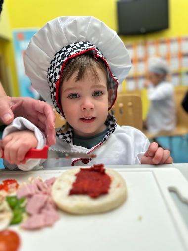 A child making a pizza at a mini chefs session at Central Link Children's Centre