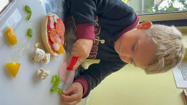 A child making a pizza at a mini chefs session at Central Link Children's Centre